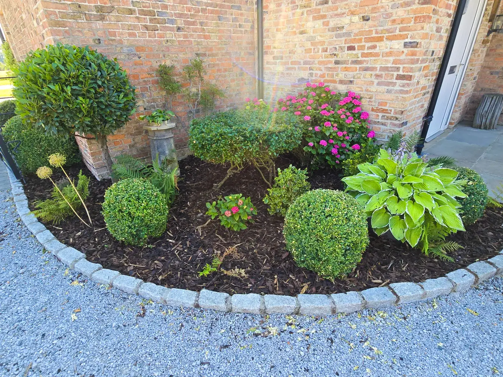 Curved corner bed with granite sett edging and topiary